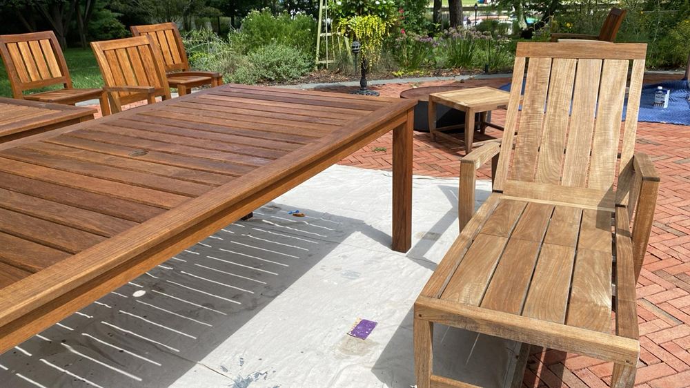 Restored teak outdoor dining table, chairs and chaise beside a pool